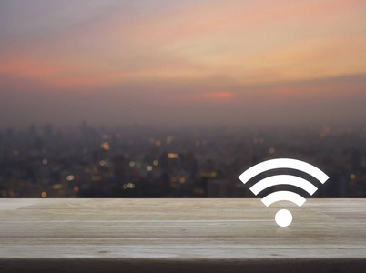 在暖光日落无线技术和互联网通信概念上, 木桌上的 wifi 按钮上空的城市景观和摩天大楼模糊