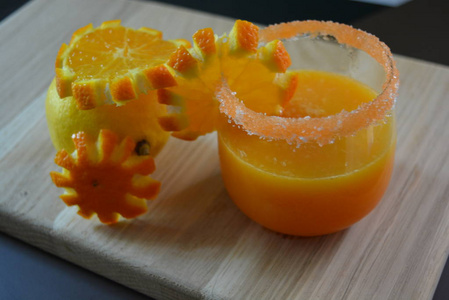 一个柠檬和一杯橙汁与胡萝卜糖环和橙色切片的轻木背景