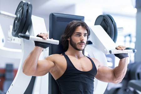 适合成人健美运动员在健身房与肩压机在一个健康的积极生活方式和健身