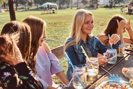 一群快乐的女友坐在餐桌旁庆祝生日在户外公园