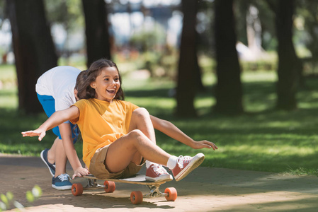 可爱的快乐的孩子玩长板在公园