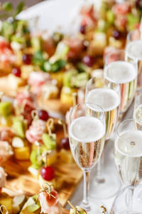 隆重的新年宴会。餐厅的餐桌上有很多香槟或葡萄酒。自助餐桌上有很多美味的小吃。小吃, bruschetta, 小甜点在木板板上