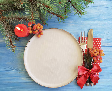 盘子, 叉子, 刀, 蜡烛, 圣诞树的树枝在蓝色的木质背景上
