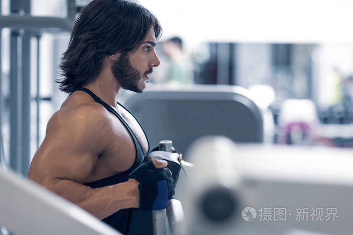 由模糊举重机械遮盖的肌肉成年男子拉金属拉杆侧面图