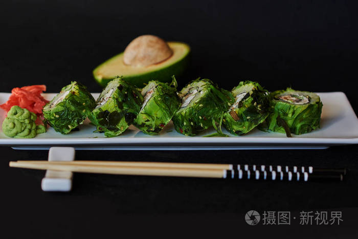 寿司套装 寿司卷上有筷子和酱油的白瓷盘子 传统的日本料理 寿司菜单 黑色背景的鲑鱼 鳄梨 黄瓜和海甘蓝卷照片 正版商用图片0rwy0f 摄图新视界