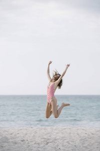 年轻女子在沙滩上跳跃