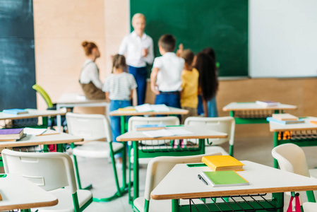 学生站在教室周围的教师与办公桌上的前景