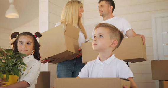 幸福的家庭有两个孩子在新家。家人在搬家的时候在新房子里装纸板箱。父亲和孩子在新的房子里
