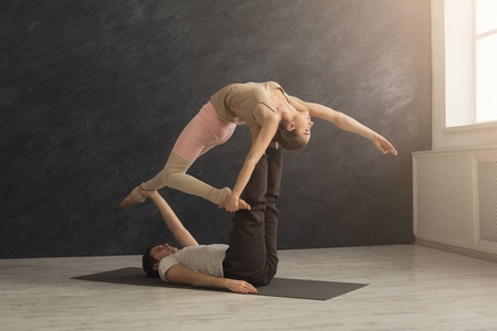 年轻夫妇在垫子上练习 acroyoga