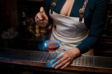 的女招待与深领口喷涂蓝色的苦涩在酒吧柜台上的优雅鸡尾酒玻璃