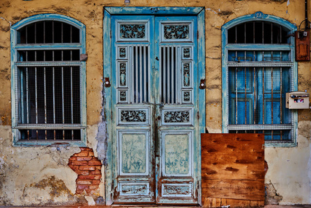 在黄色水泥墙上的老式窗户和门可以用于背景。城市腐朽的垃圾背景