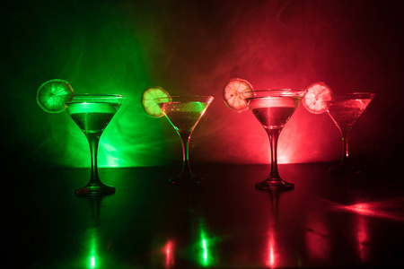 几杯著名的鸡尾酒马提尼, 拍摄在酒吧与黑暗色调的雾背景和迪斯科灯。俱乐部饮料的概念。选择性聚焦