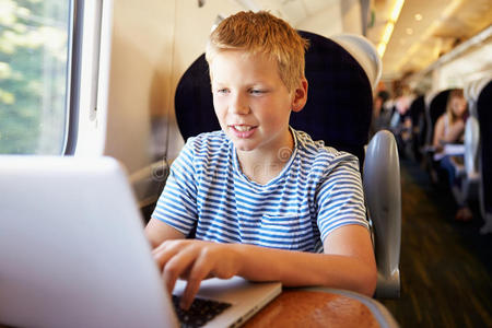 火车旅行中使用笔记本电脑的男孩