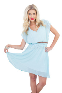 身穿蓝色连衣裙的快乐金发模特抱着裙子摆姿势
