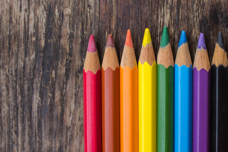 在木质背景上削尖彩色铅笔。在木桌上上色铅笔。彩色铅笔锋利的滑动特写。在彩虹的颜色的铅笔。明亮的背景。欢快的颜色。多彩多姿的石板。