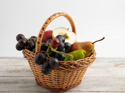 篮子里有水果李子, 葡萄, 苹果, 梨。放在木板上