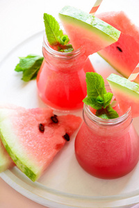 夏季西瓜冰沙装饰薄荷叶在粉红色的背景。夏日饮品概念