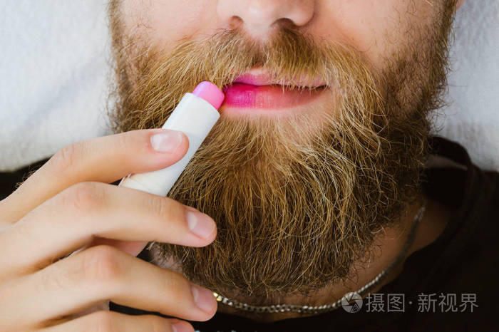 在他的嘴唇上涂上彩色粉红色唇膏唇膏的胡子男子关闭.