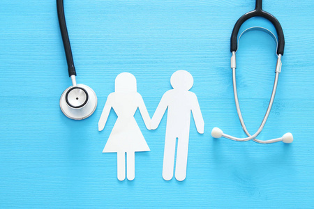 健康保险。听诊器和夫妇在木桌上的概念形象。顶部视图