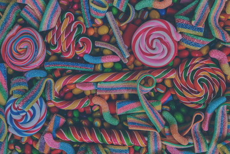 五颜六色的明亮的各式糖果手杖和彩虹彩色螺旋棒糖, 分散果酱, 软糖和不同颜色的圆形糖果。顶部视图。糖果背景