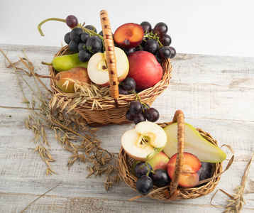 篮子里有水果李子, 葡萄, 苹果, 梨。放在木板上