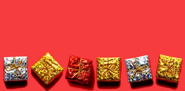 圣诞节图案由红色金色与银色礼品盒在红色背景下隔离。多彩色调和冬季概念。平躺