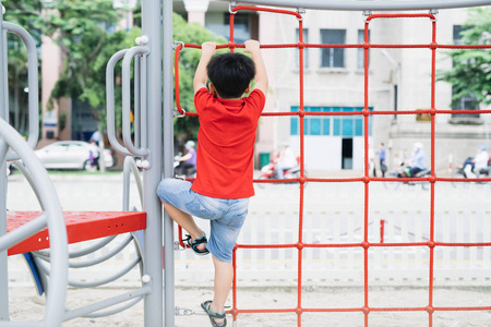 小男孩在操场上玩单杠上