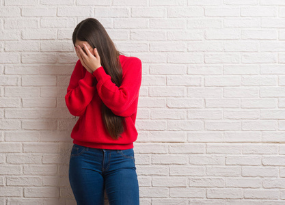 中国人的脸年轻的中国女人在砖墙上带着悲伤的表情捂着脸, 一边哭着.