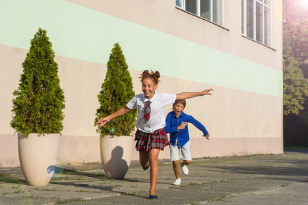 笑学童一个女孩和一个男孩在校园里快乐地奔跑着。