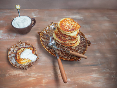 新鲜做的乳酪蛋糕, 酸奶油在陶瓷板材以猫头鹰的形式, 餐具在褐色木背景上