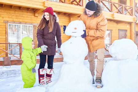 白人夫妇与小男孩做雪人, 而度过冬天周末出城