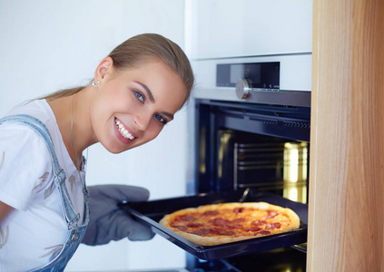 快乐的年轻女人，烹饪比萨饼在家里