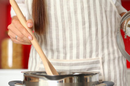 烹饪的女人，在厨房里用木勺
