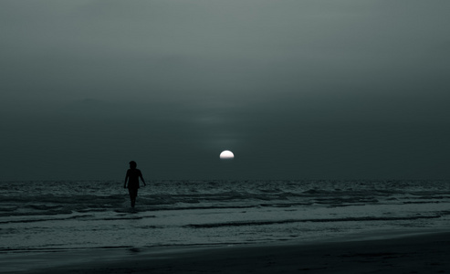 剪影人漫步在海滩上日落时间