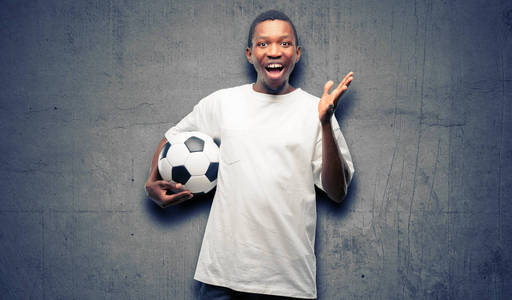 非洲黑人举行足球高兴和惊喜欢呼表达哇手势照片