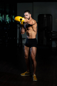 英俊的男子在黄色拳击手套拳击在健身房健康生活方式的概念关于拳击电影的想法