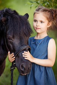 可爱的小女孩和小马在一个美丽的公园