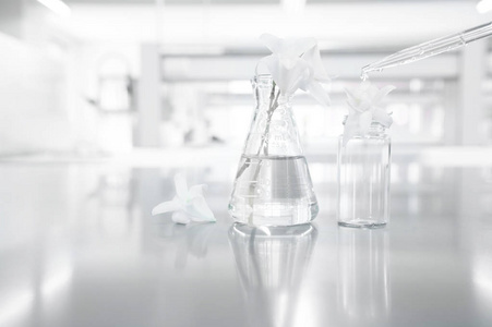 在化妆品研究科学实验室背景下的玻璃瓶中的白色兰花花