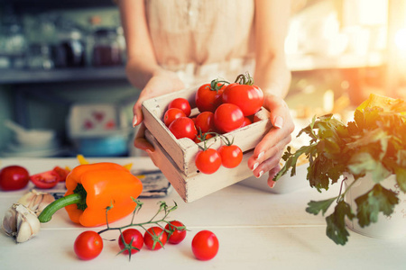 拿着新鲜蔬菜的小箱子的女人。灿烂的夏季丰收。健康的有机食品概念。素食蔬菜, 有机食品, 原料。天然营养饮食。色调图片
