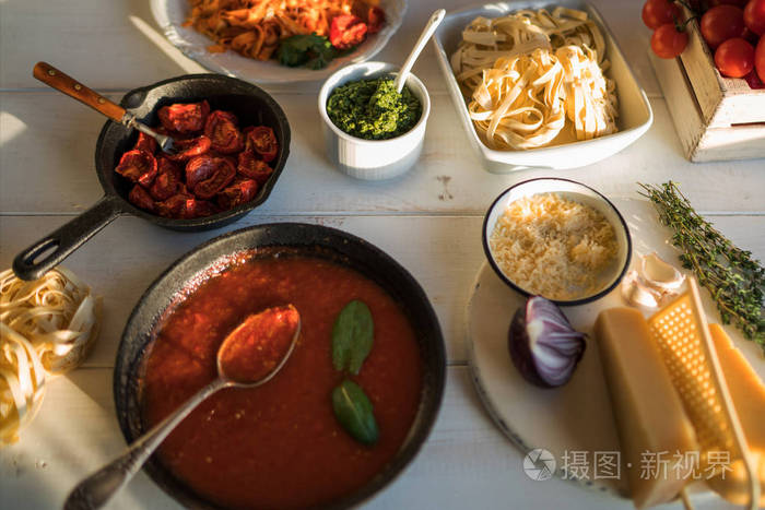 意大利面配辣番茄酱, 干酪和罗勒。盘子里配有美味的面食芝士锅里有有机番茄酱和厨房木板的木桌, 上面的景色。烹饪产品。软焦点