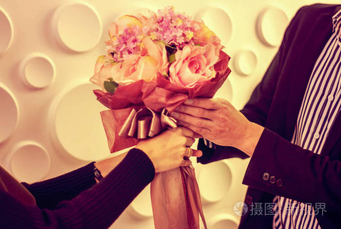 年轻人捧着一束玫瑰花束在手为一个年轻的女孩情人, 温暖的颜色, 复古风格, 浪漫的概念照顾情侣