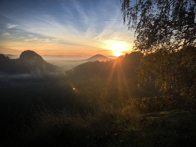 史诗般的日出光在一个台面的顶峰在德国萨克森瑞士国家公园。山的范围与光和雾。远足和攀登在 Elbe 砂岩山的美妙的山范围