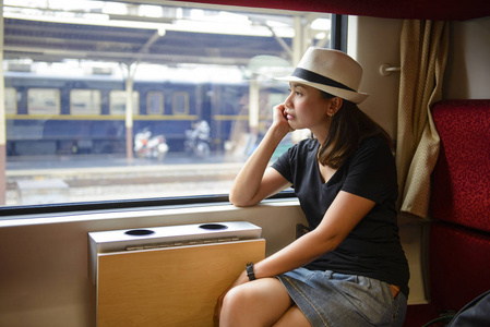 火车窗外年轻的亚洲妇女坐在火车上看窗外照片