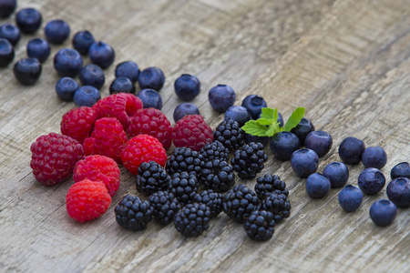 混合的黑莓, 覆盆子, 蓝莓在旧的木桌背景。具有复制空间的顶部视图
