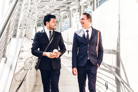 两个微笑的商人同事在黑色西装说话和步行. 现代城市商务人士的策略探讨