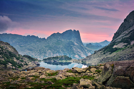 美丽的五颜六色的日出风景夏天风景如画的山湖以石头和岩石在多云天空背景