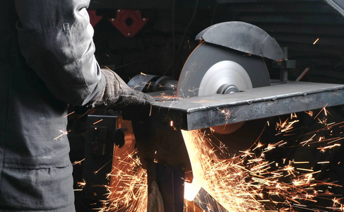 特写男子手用圆锯切割金属.火花飞向彼岸照片