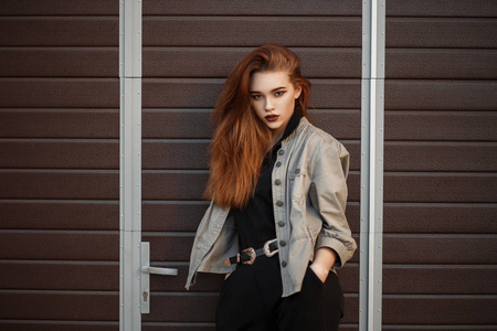 漂亮的年轻模特女孩在时尚夹克和黑色马球衬衫摆在门口附近