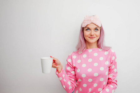 快乐的少妇喝早晨的咖啡。美丽的女孩粉红色的睡衣和 sleepmask