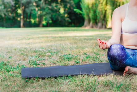 在大自然中练习瑜伽的年轻女子。坐在绿色的草地上沉思。绿色背景与色调效果。健康和体育的概念。复制文本空间